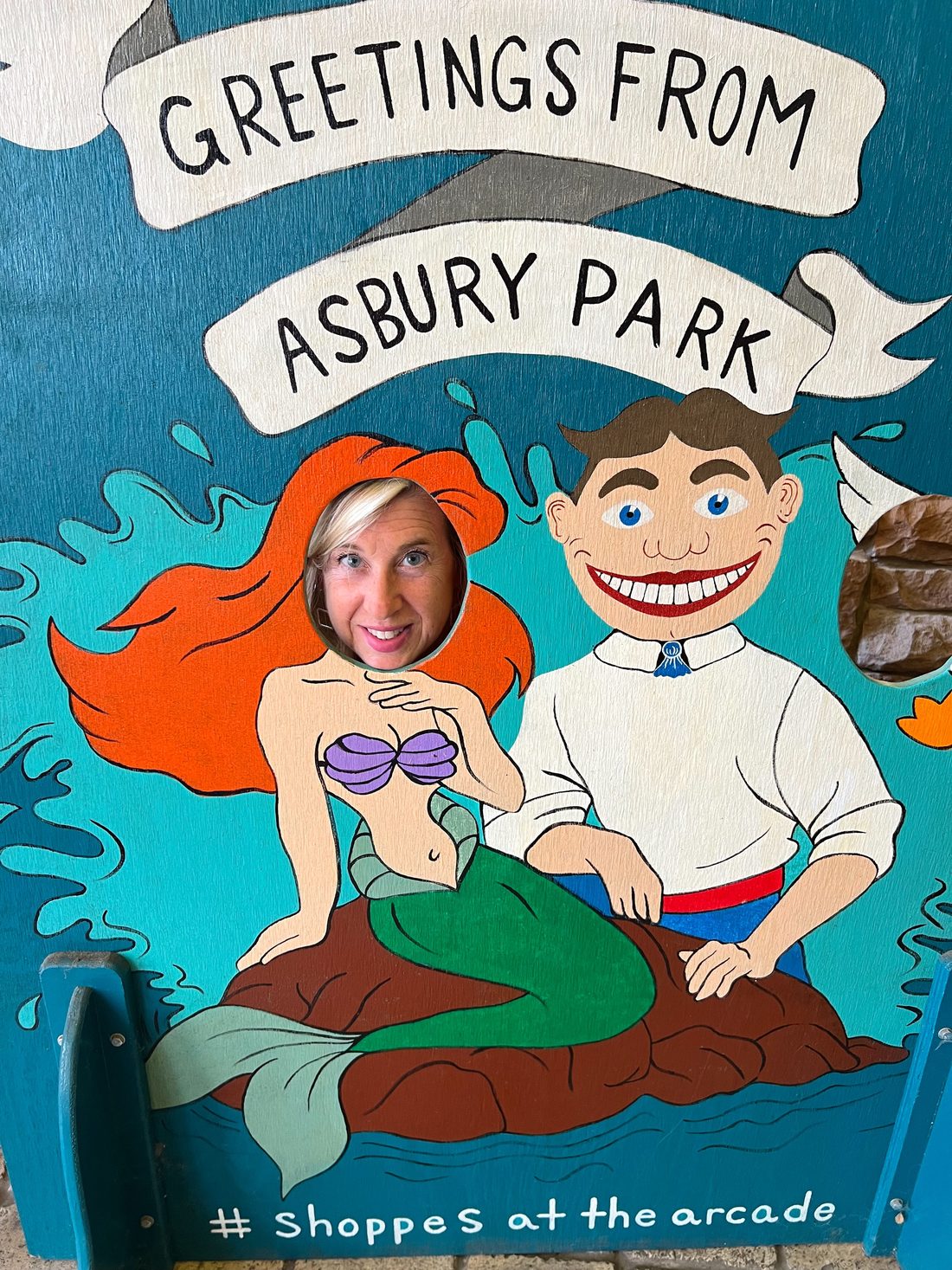 Gil's wife in a Greetings from Asbury Park mermaid photo board