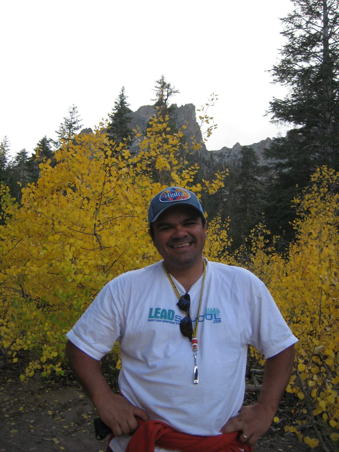 Gil smiling in front of golden fall aspens below a granite peak