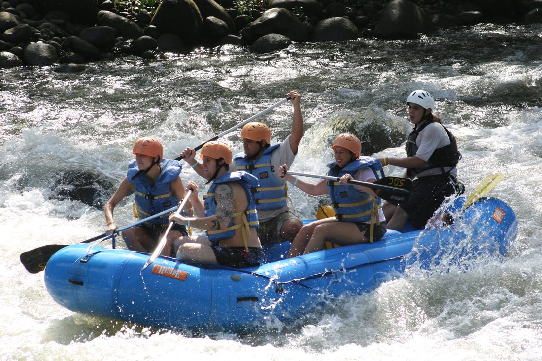 Gil paddling a whitewater raft through rapids