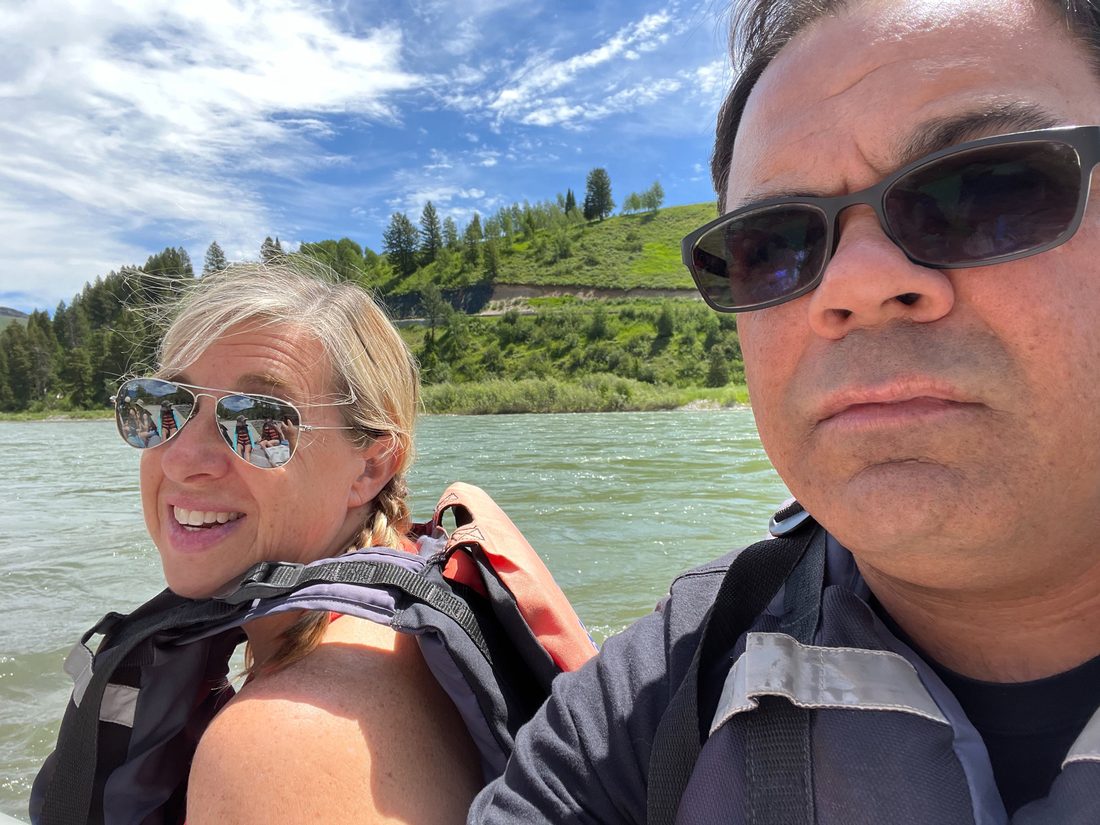 Gil and his wife in life jackets on a river float