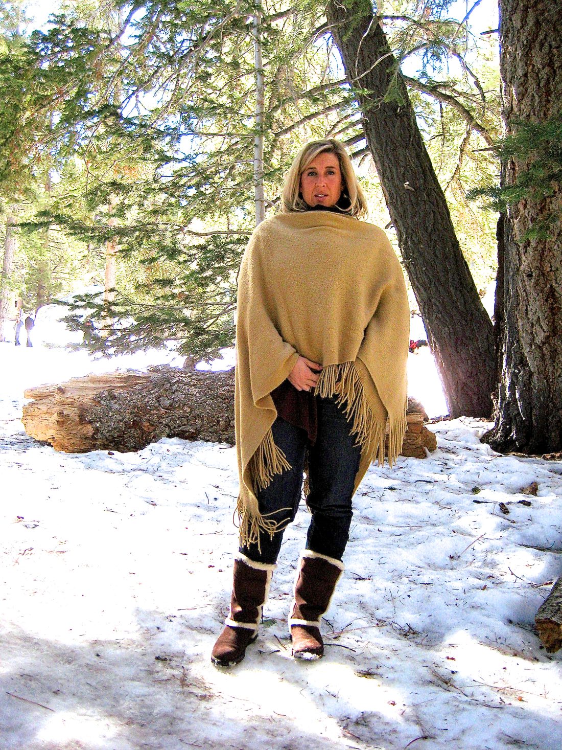 Gil's wife in a wool wrap standing in the snowy pines